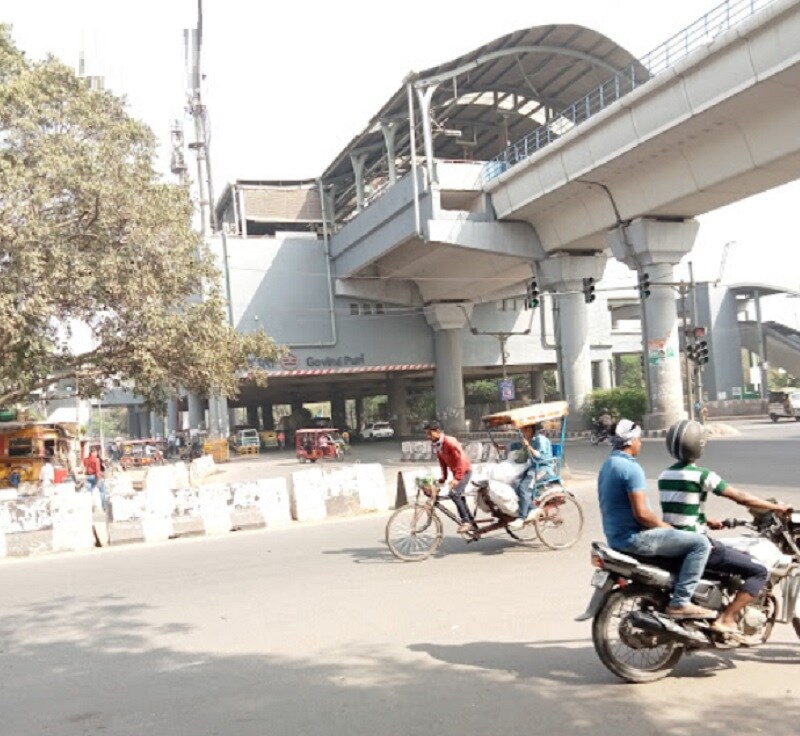 Govindpuri_a man riding a motorcycle down a street next to a bridge