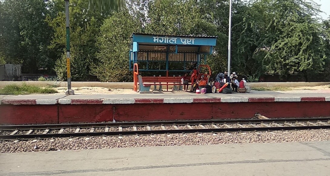 Mangolpuri_people sitting on a bench next to a train
