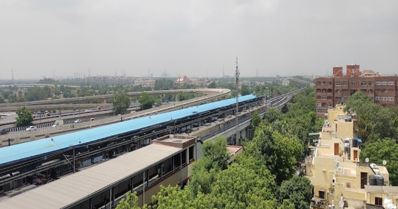 Mayur Vihar_a train traveling down train tracks next to tall buildings