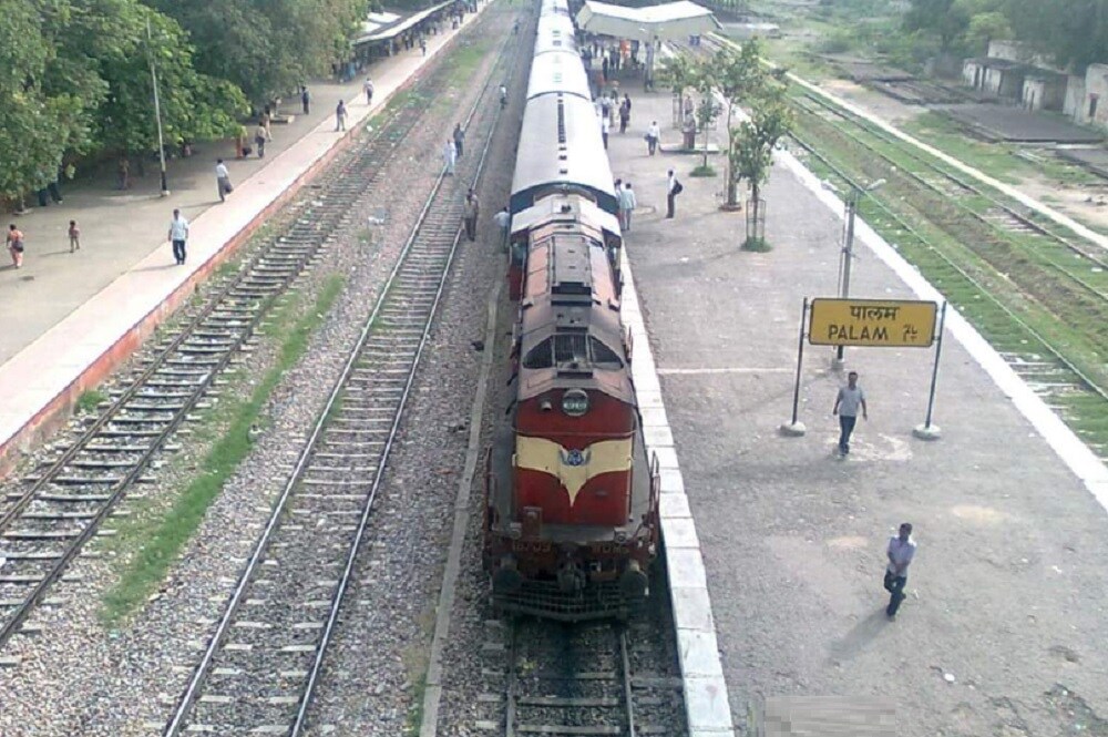 Palam_a train traveling down tracks next to a train station