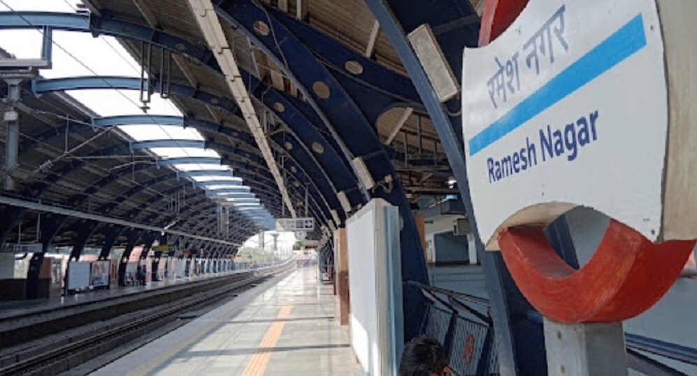 Ramesh Nagar_a train station with a train on the tracks