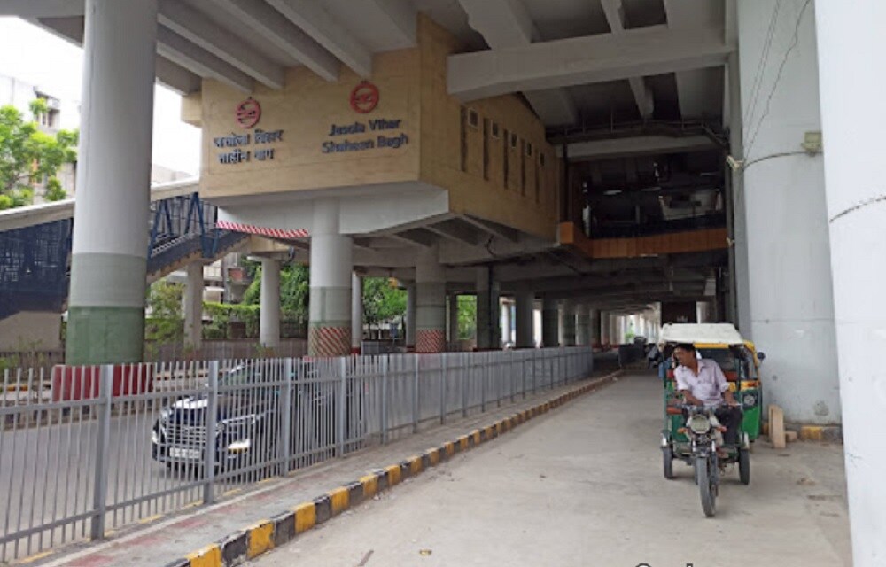 Shaheen Bagh_a man riding a bike down a street next to a train