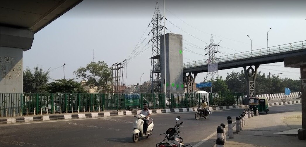 Sahibabad_a man riding a bike down a street next to a bridge
