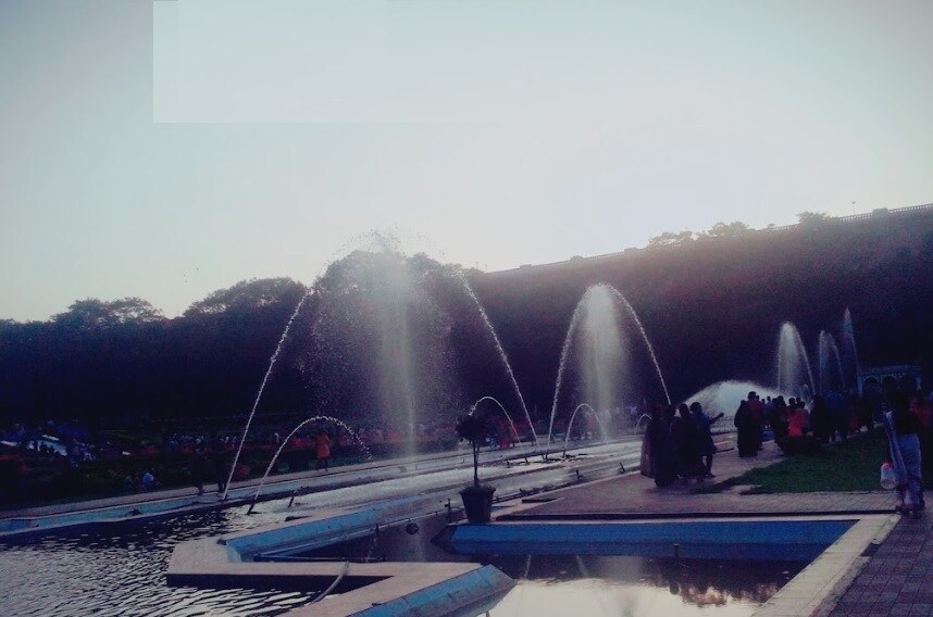 Vrindavan Garden_people standing on a pier with umbrellas