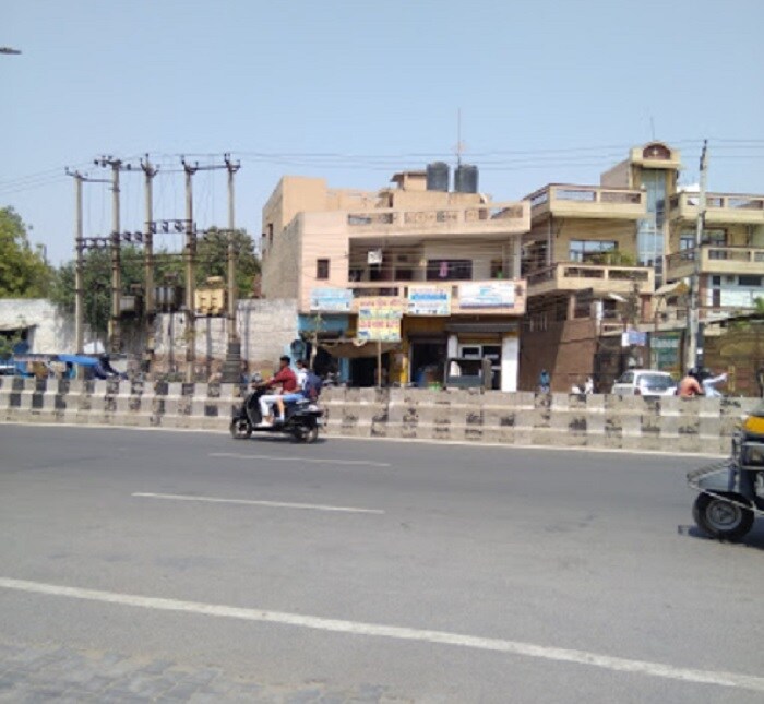 Ashok Vihar_a man riding a motorcycle down a street next to a building