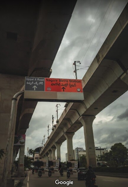 Nagole_a street sign with a train crossing over it