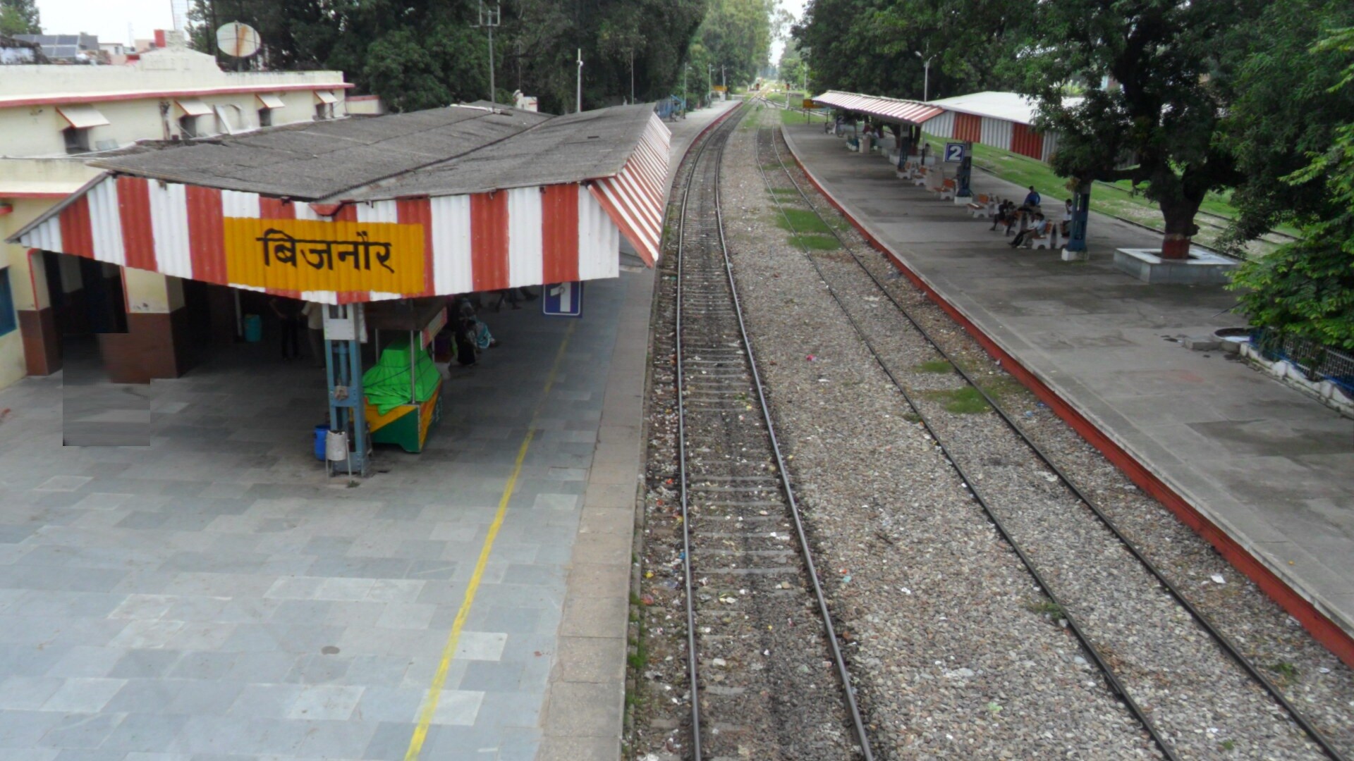 Bijnor_a person walking down a train track next to a train station