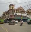 Wazirganj_a man riding a motorcycle down a street next to a tall building