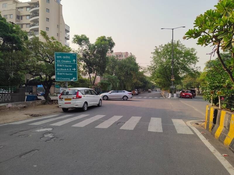 Sector 44_a car driving down a street next to tall buildings