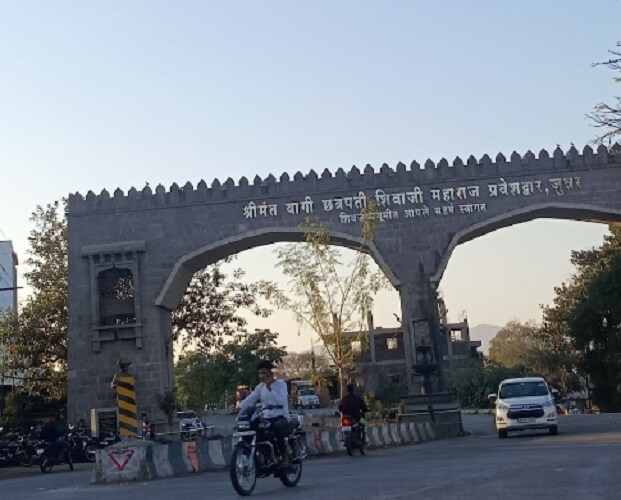 Junnar_a man riding a motorcycle down a street next to a bridge