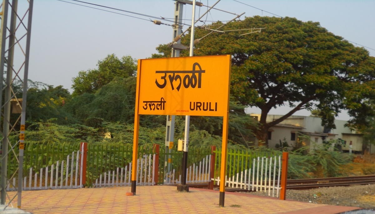 Uruli Kanchan_a sign on a pole with a street sign on it
